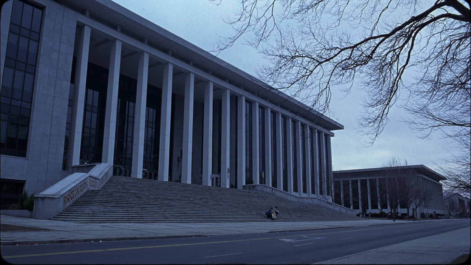 The columned facade and empty steps of a federal courthouse under a grey sky