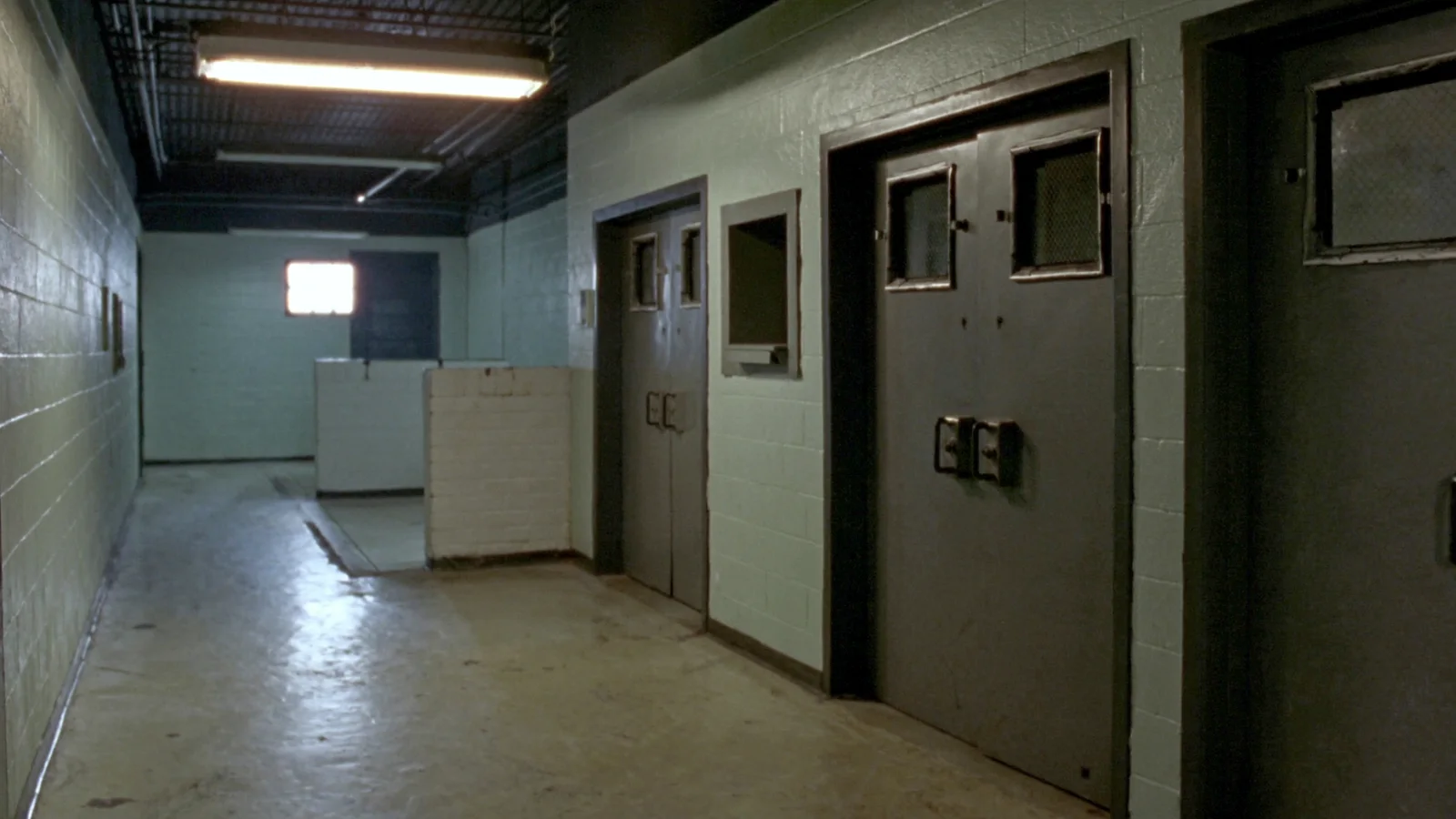 An empty corridor of heavy steel doors inside an institutional detention building