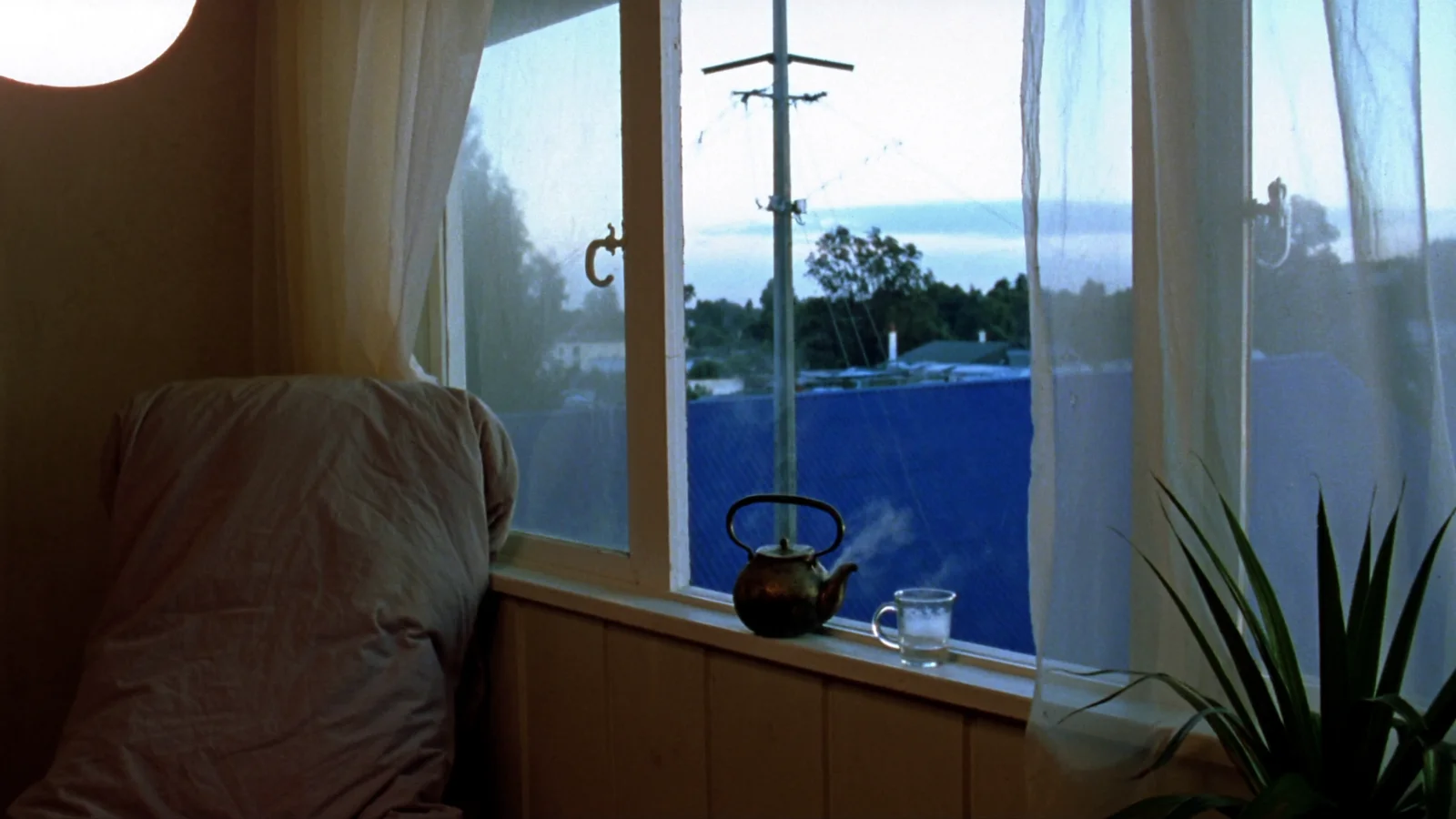 Soft morning light falling across a windowsill with a folded blanket and a cooling mug of tea