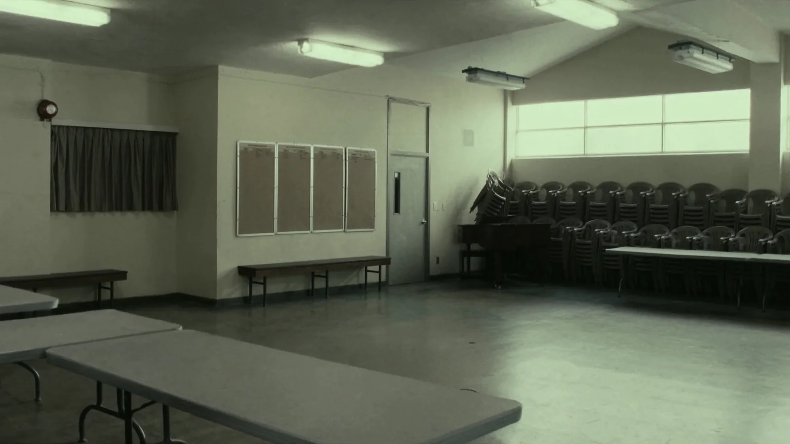 An empty parish hall with stacked chairs and folding tables pushed against the walls