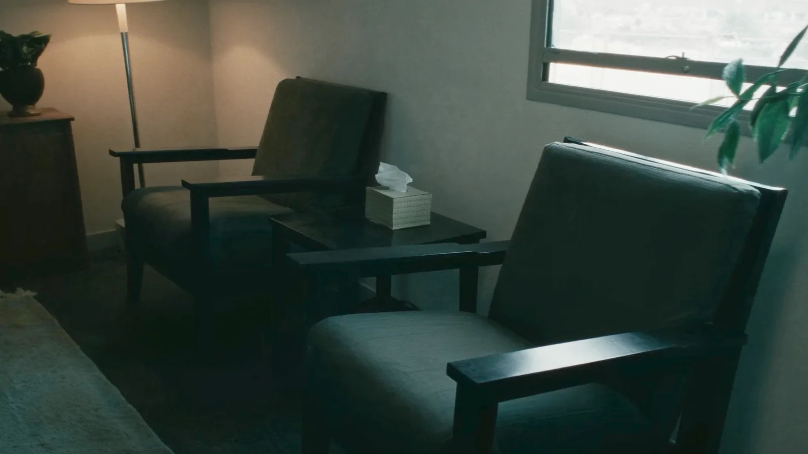 Two empty armchairs facing each other in a quiet therapist&rsquo;s office with soft daylight