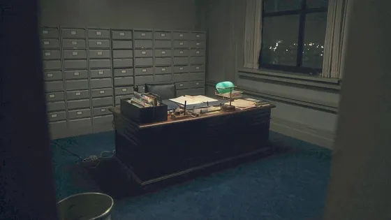 A dark private office at night with ledgers and a single desk lamp
