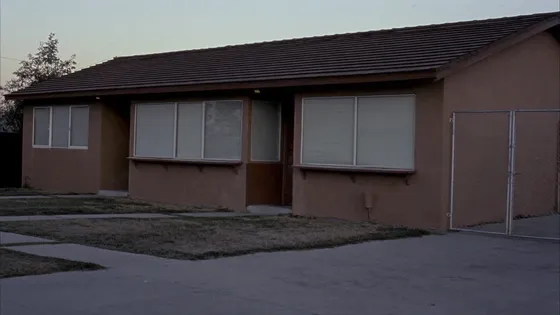 A plain single-story group home at dusk with closed blinds