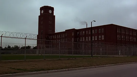 A red brick state youth training school behind chain-link fencing